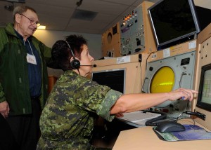Retired Air Traffic Control Officer, Captain Peter Morin, watches Master Corporal Heather Moss, an Air Traffic Controller at 19 Wing Comox, use the Precision Approach Radar for the last time to guide a CF-18 pilot to a landing before the system was decommissioned on June 28, 2013. Image by Cpl Jennifer Chiasson ©2013-DND-MDN CANADA